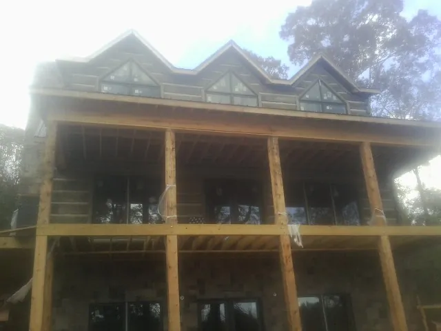 Dormers and porch framing on a large log home under construction — Roof Coating work by our crew in Sterling
